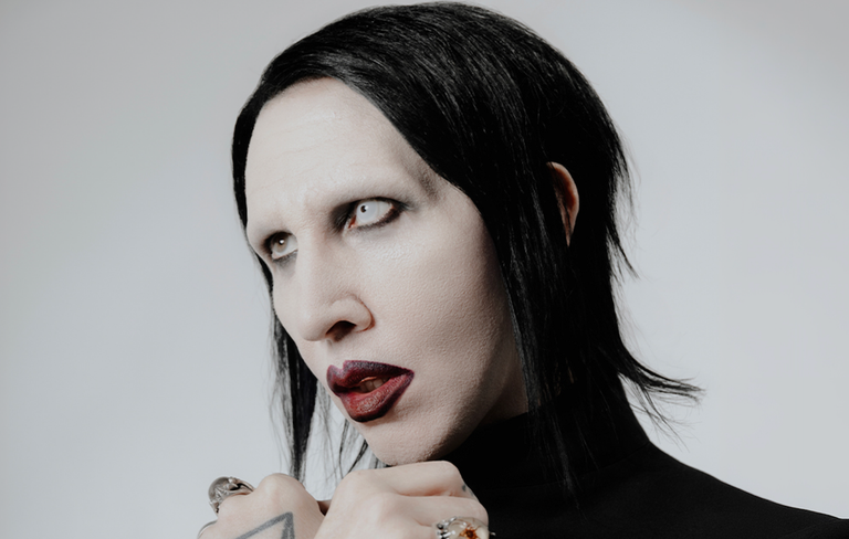 Promotional portrait of industrial rock musician Marilyn Manson featuring signature dark makeup and white contact lens.